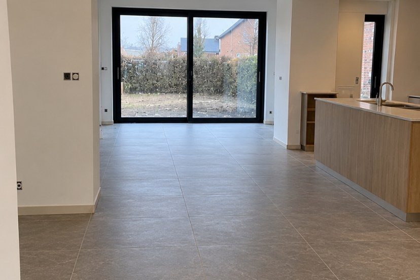 Lichte, stofvrije leefruimte met tegelvloer en grote schuiframen